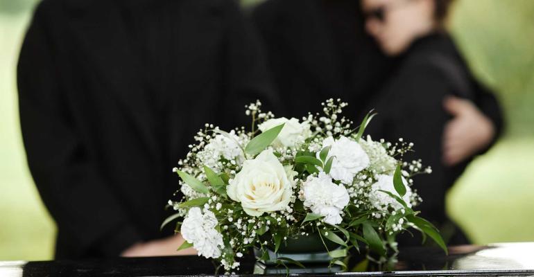 family at funeral in front of casket with bouquet of flowers